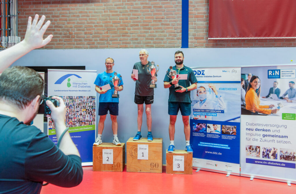 Sieger mit Pokalen auf Tischtennisturnier-Podest