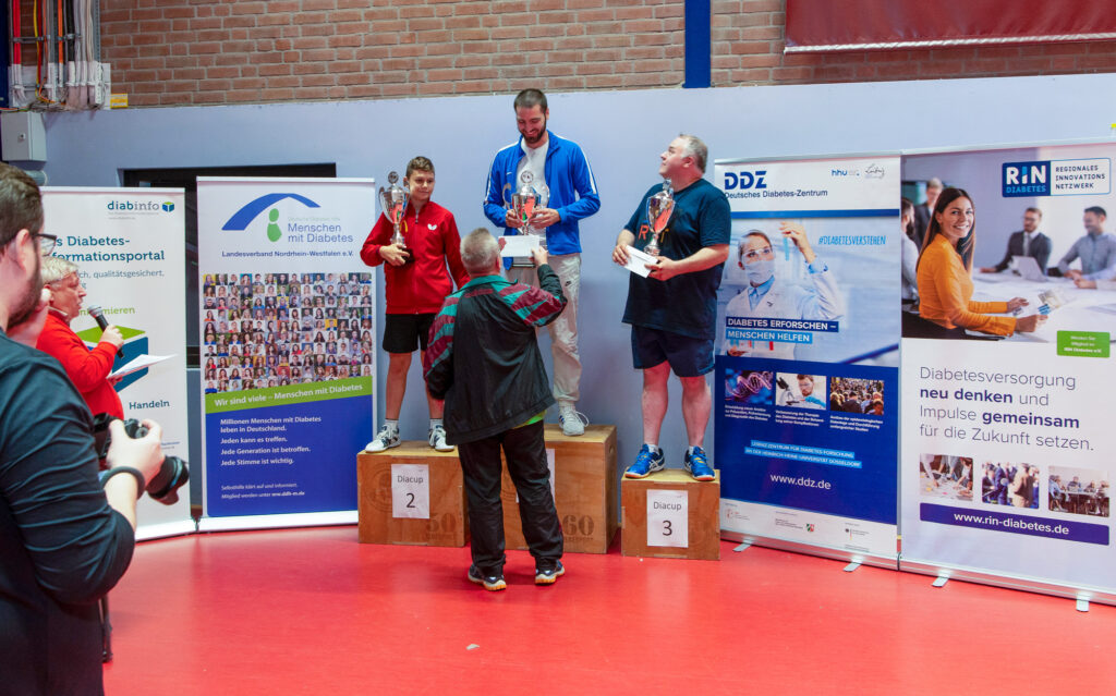 Männer auf Sportpodest mit Diabetes-Informationsständen