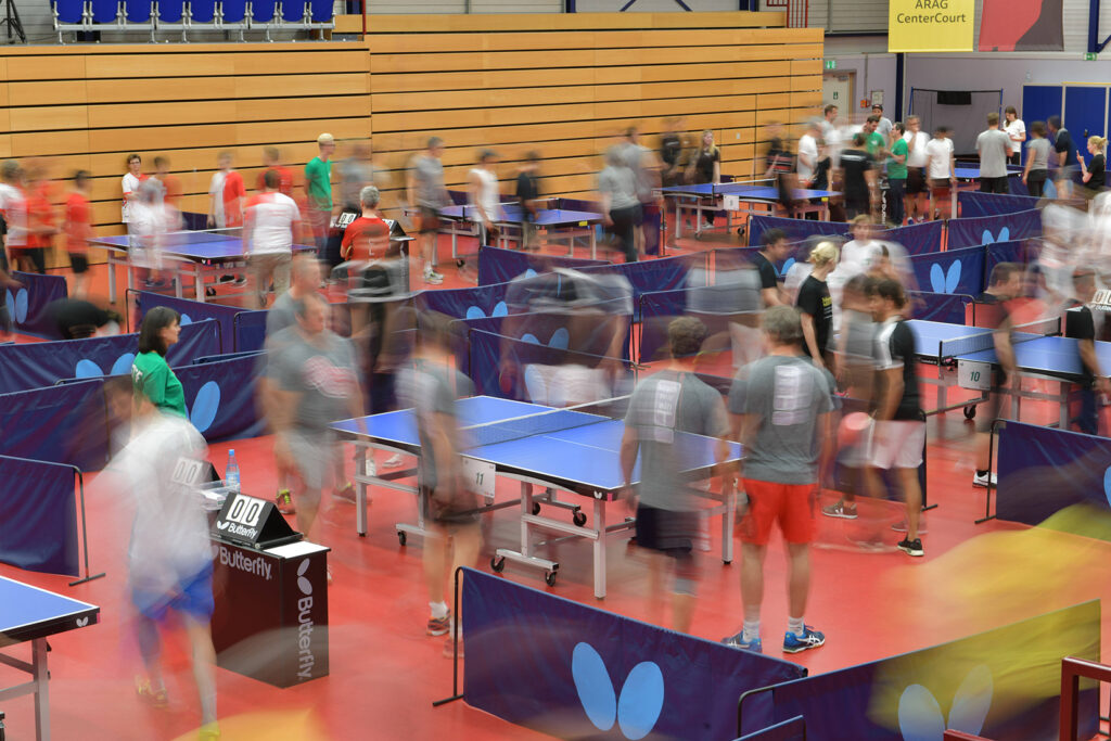 Tischtennisturnier in einer Sporthalle mit vielen Spielern und Zuschauern