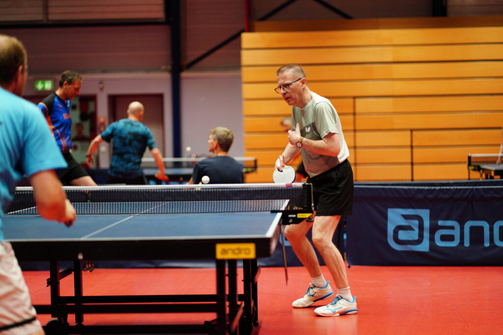 Ältere Männer spielen Tischtennis in einer Sporthalle