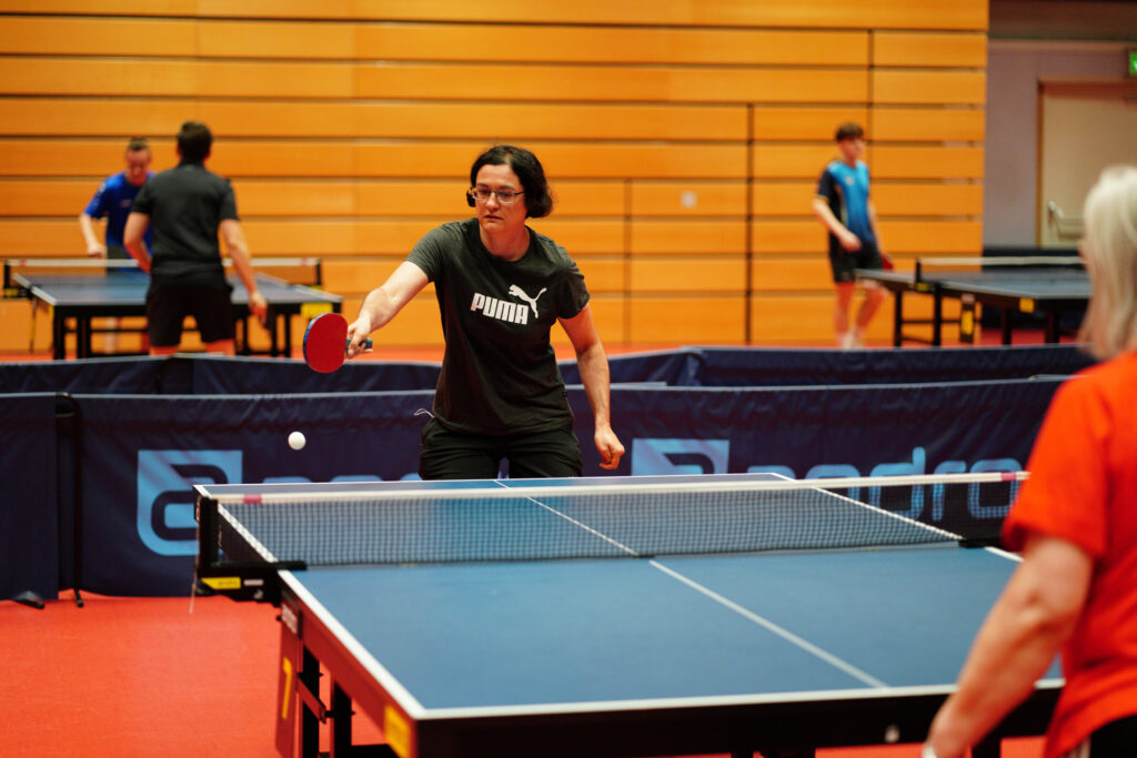 Frauen spielen Tischtennis in einer Sporthalle