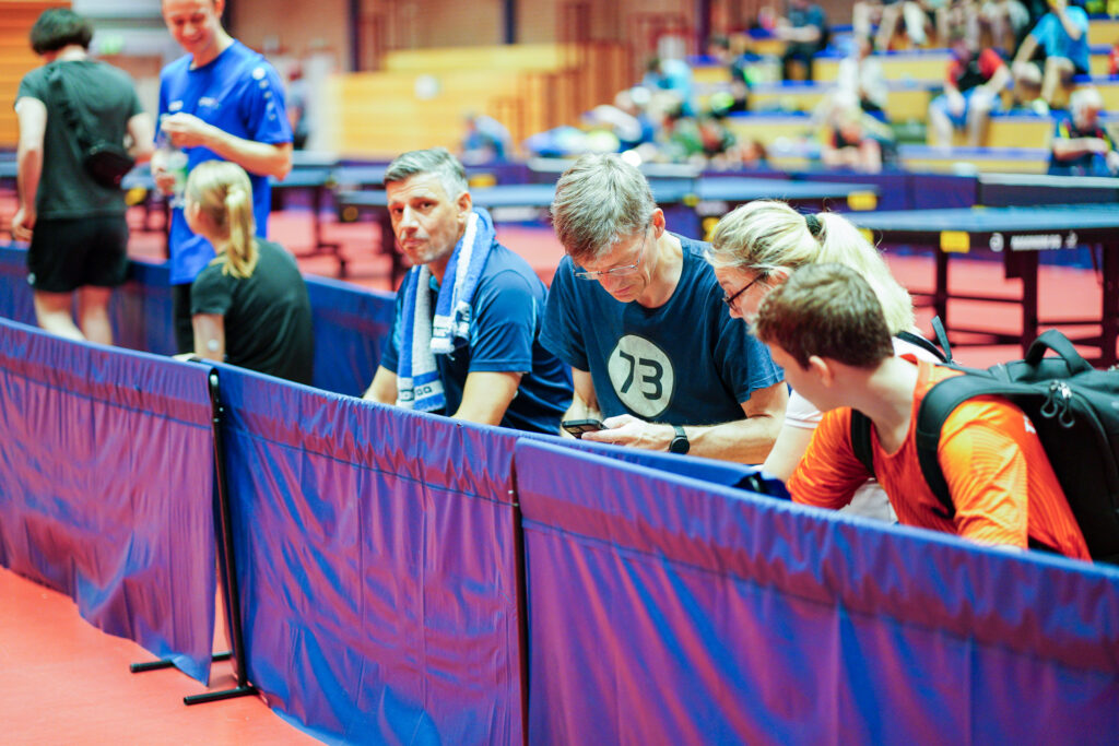 Menschen warten in Sporthalle auf Tischtennis-Wettkampf