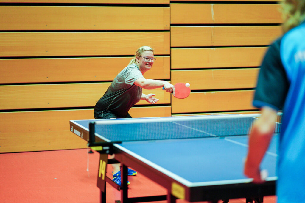 Tischtennisspieler schlägt Ball in einer Spielhalle