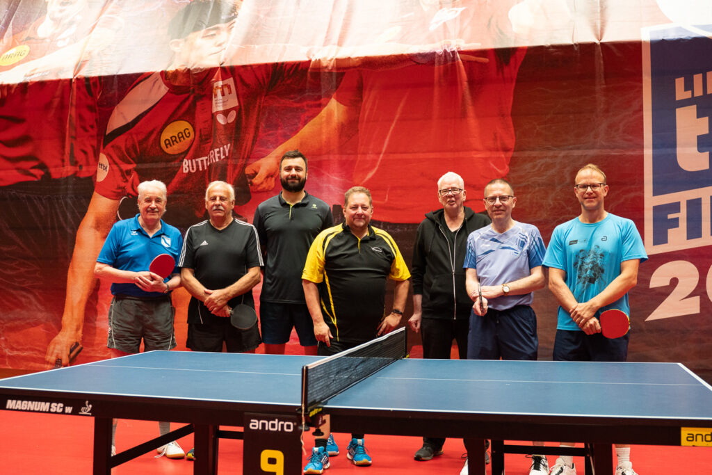 Senioren Tischtennis-Spieler posieren bei Turnier in Sporthalle