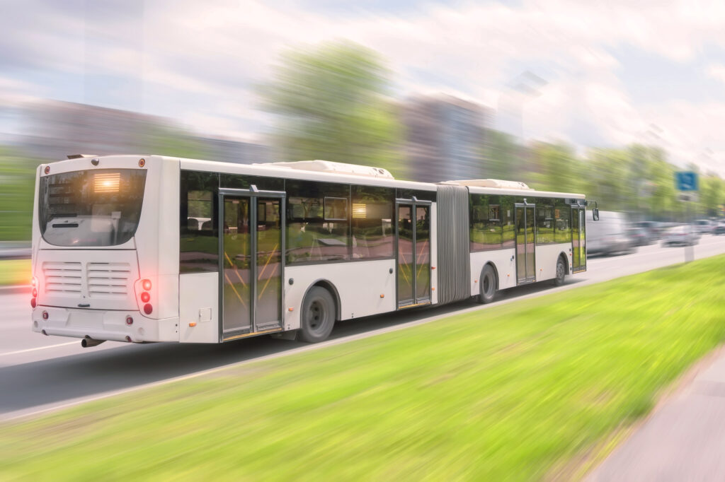 Schnell fahrender Gelenkbus auf grüner Straße